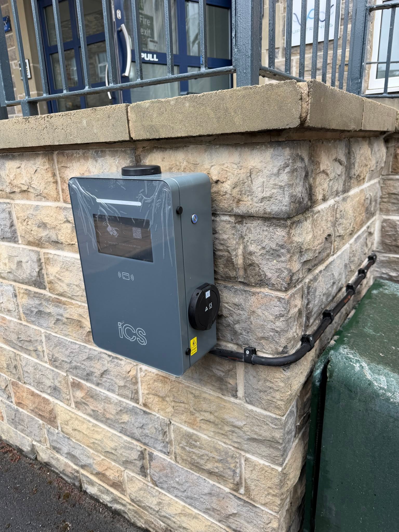 Wall-mounted commercial EV charging unit on a stone building