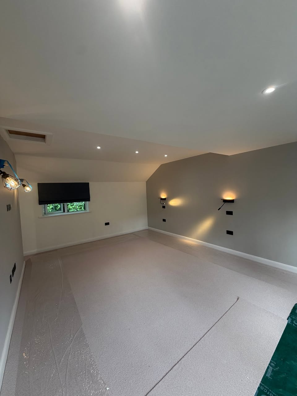 Finished room with recessed spotlights, wall lights and black electrical accessories